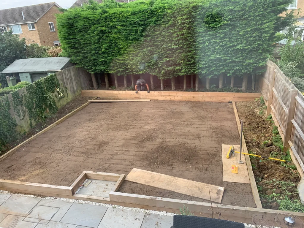 Levelled garden after man and digger site preparation, with a new sleeper retaining wall installed along the boundary, ready for landscaping.