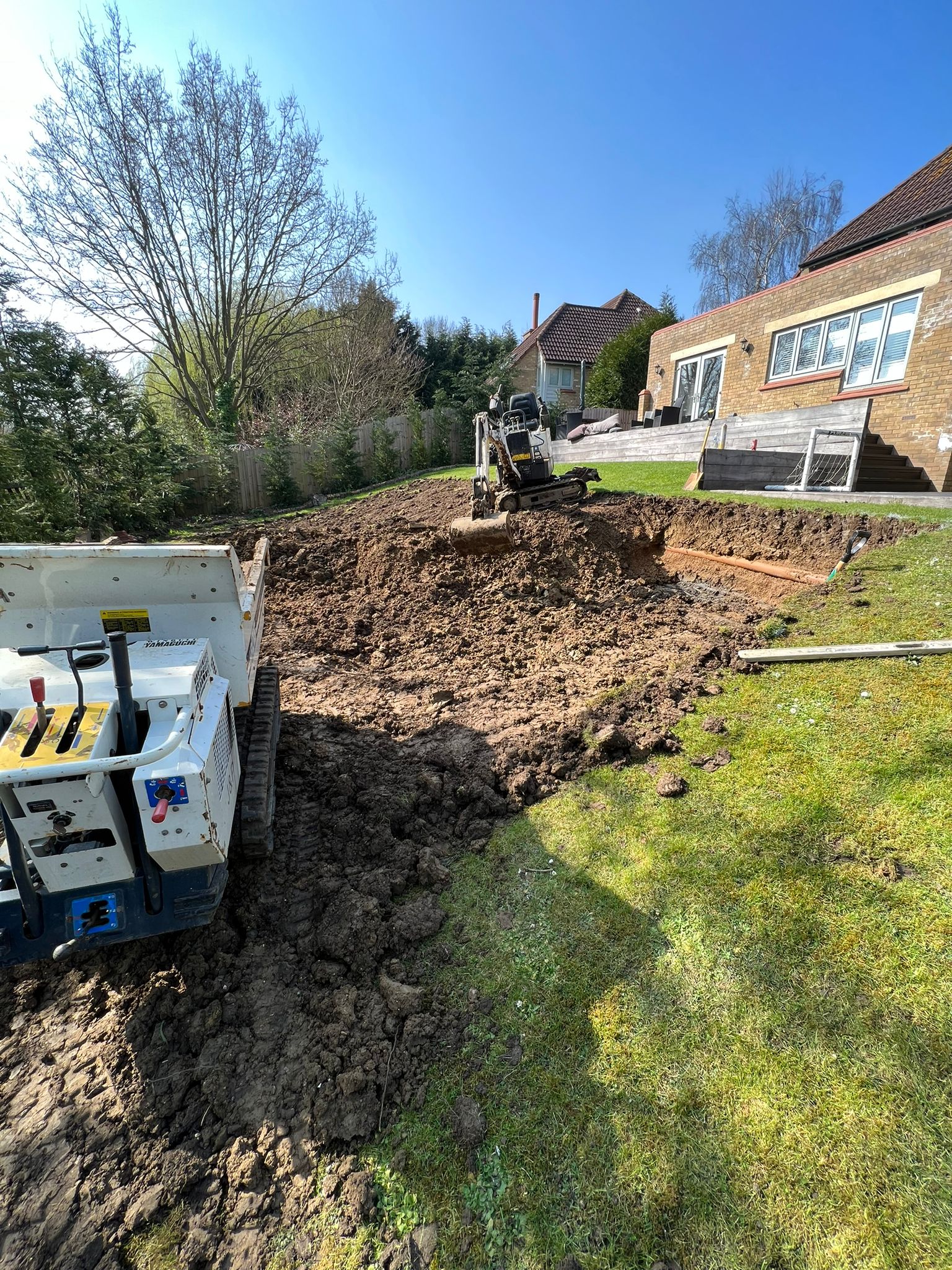 Operated mini digger and a tracked dumper working together excavating a sloped back garden in Newport Pagnell on a man and digger groundwork job.