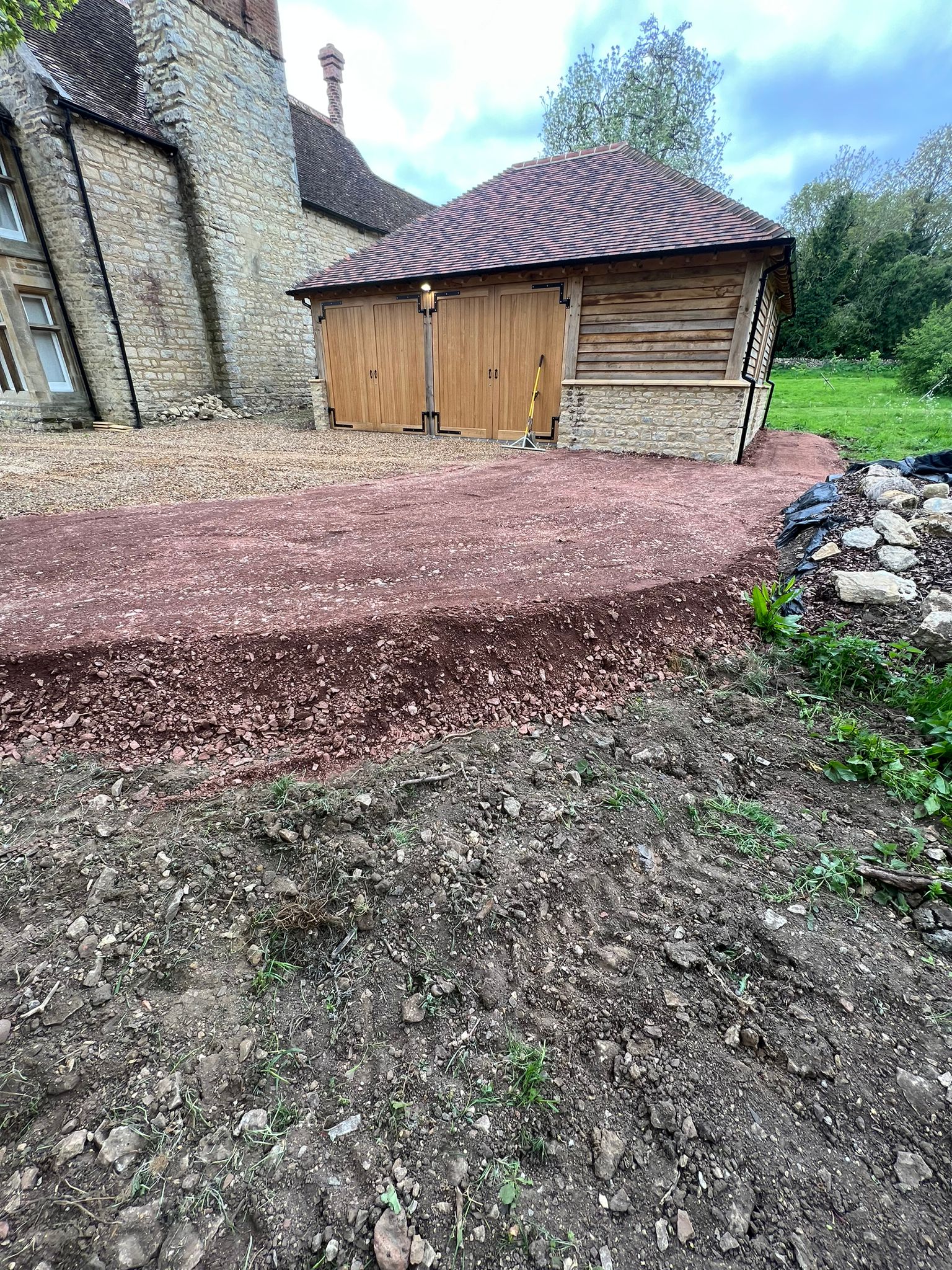 Freshly laid sub-base for a new driveway and hardstanding at a stone period property in Newport Pagnell after man and digger groundwork.